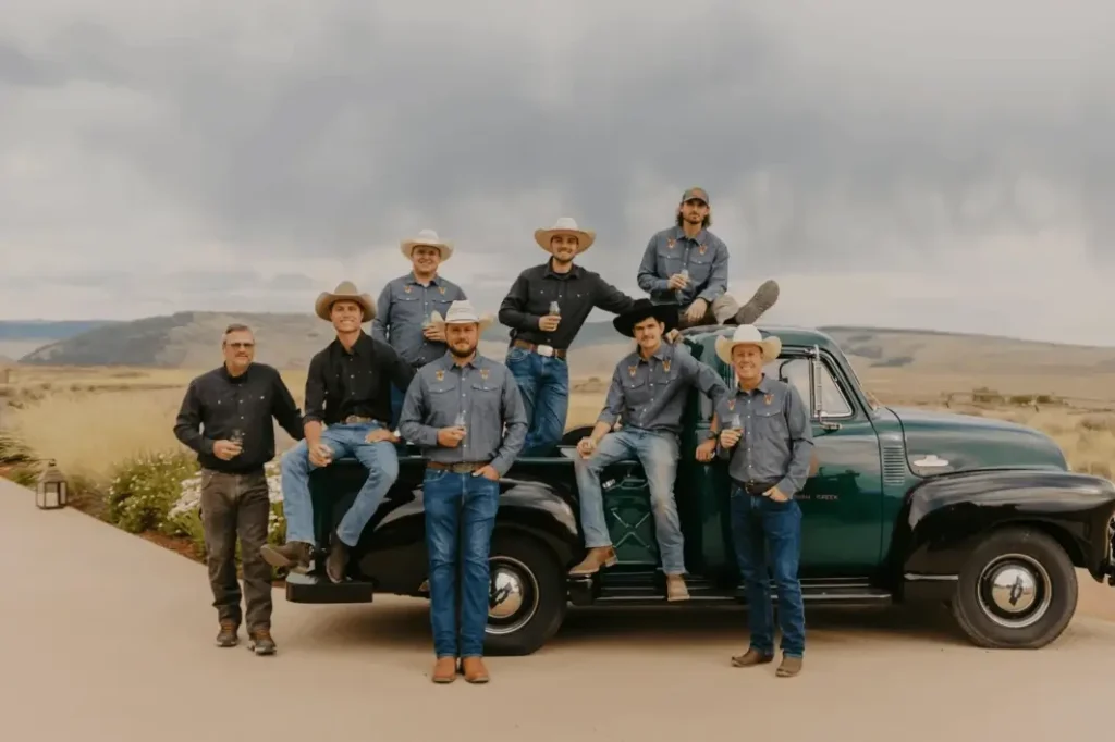 Brush Creek Distillery team all dressed in western outfits leaning up against and sitting in the bed of an old time truck